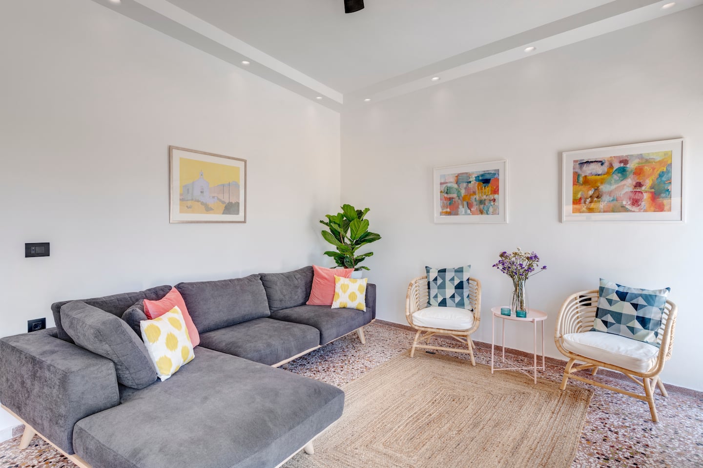 Living room with grey sofa, rattan chairs and original art