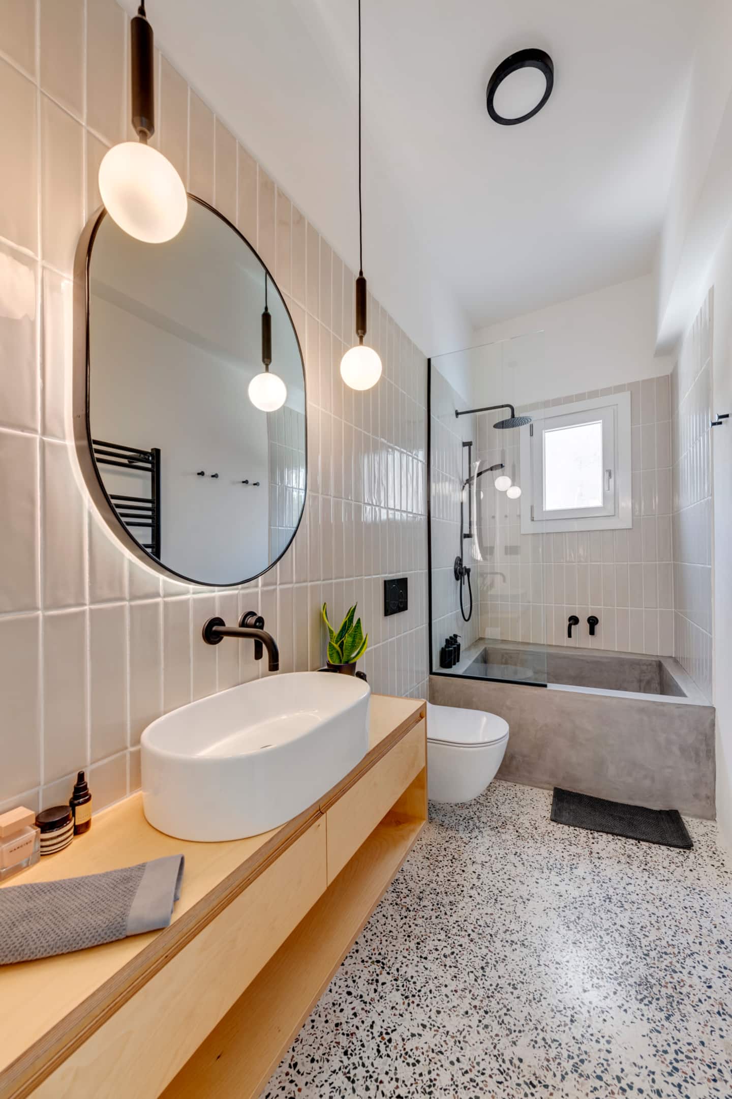 Bathroom with terrazzo floor, oval mirror and birch vanity